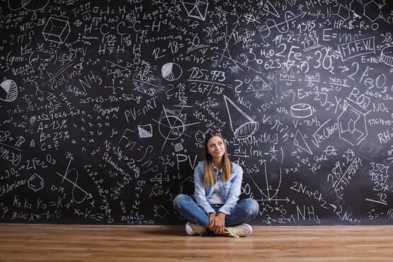A-level school girl in front of big maths blackboard Bournemouth. Studio shot on black background.